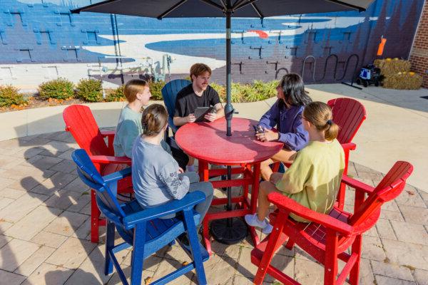 A group of students having a conversation at a table on the Brandt Student Center patio